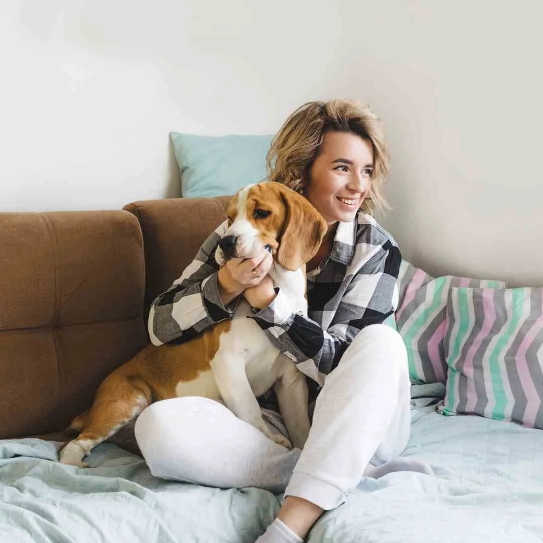 A woman cuddling her dog on a couch at home